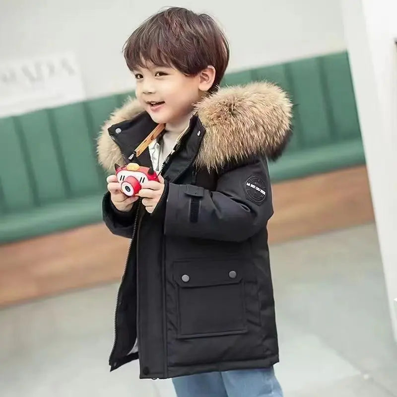 Boys winter coat with hood in black, worn by a boy holding a toy camera, fluffy hood trim and snap-flap pocket
