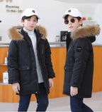 Boys winter coat with hood in black worn by two boys, longer cut past the hips with fluffy hood trim