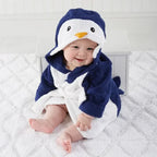 Kids hooded animal bathrobe, Navy Penguin design with white front and orange beak, baby sitting on a white rug