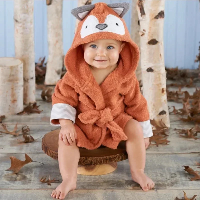 Kids hooded animal bathrobe, orange Fox design with tie belt, baby seated on a wooden stool among autumn leaves
