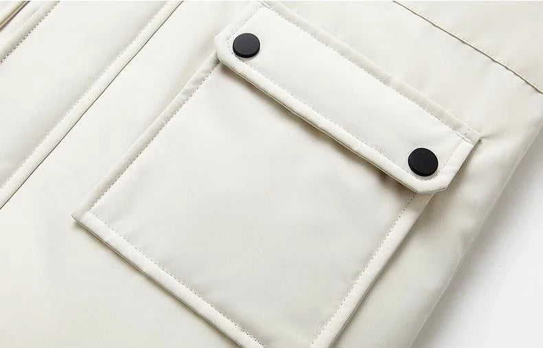 Boys winter coat close-up in cream showing the snap-flap front pocket with two black snaps and stitched edges