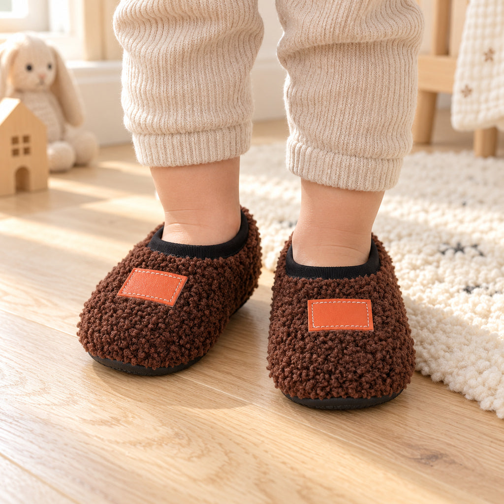 Toddler wearing brown Lumiwee Burrow non-slip slipper socks on a wood floor