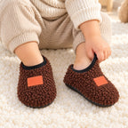 Toddler pulling on brown Lumiwee Burrow plush slipper socks