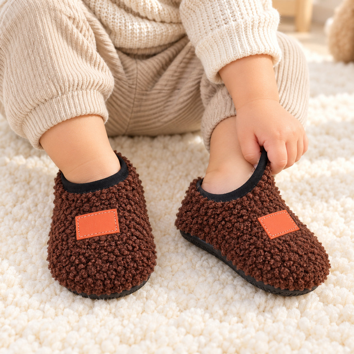Toddler pulling on brown Lumiwee Burrow plush slipper socks