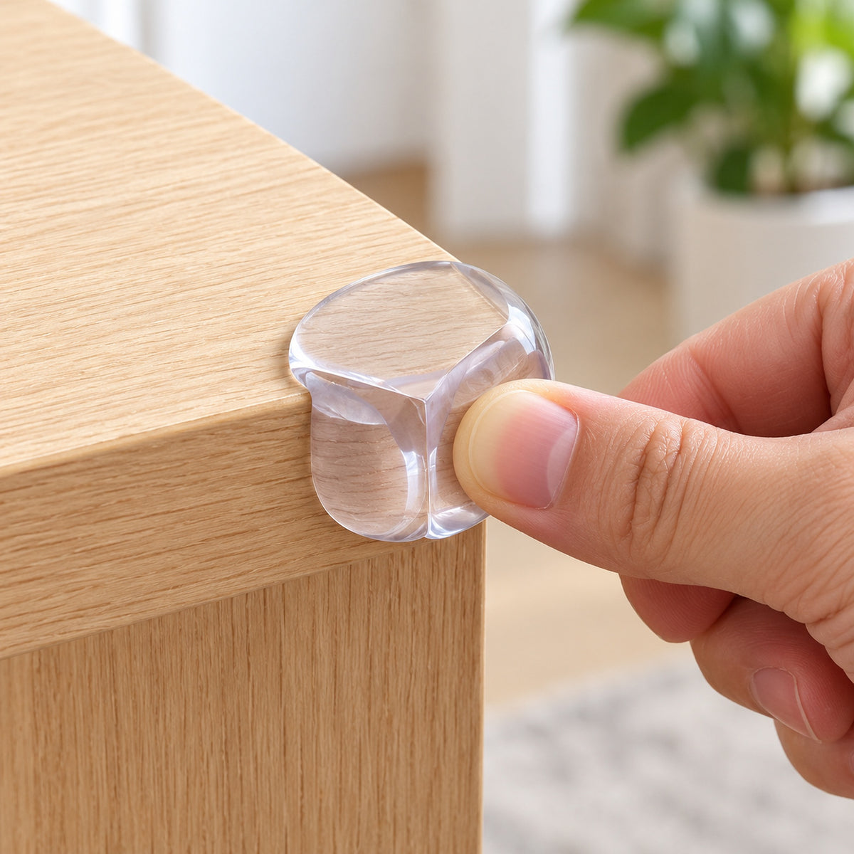 Adult pressing a clear Lumiwee corner guard onto a light-oak table corner