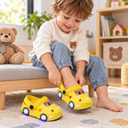 Seated toddler sliding a foot into yellow Lumiwee light-up car clogs