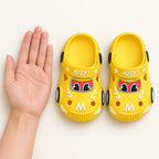 Yellow Lumiwee toddler car clogs beside an adult hand for scale