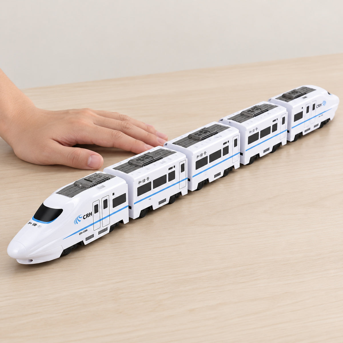 Five-car Lumiwee Dash bullet toy train beside an adult hand for scale