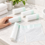 Five rolls of Lumiwee disposable potty liners beside an adult hand for scale