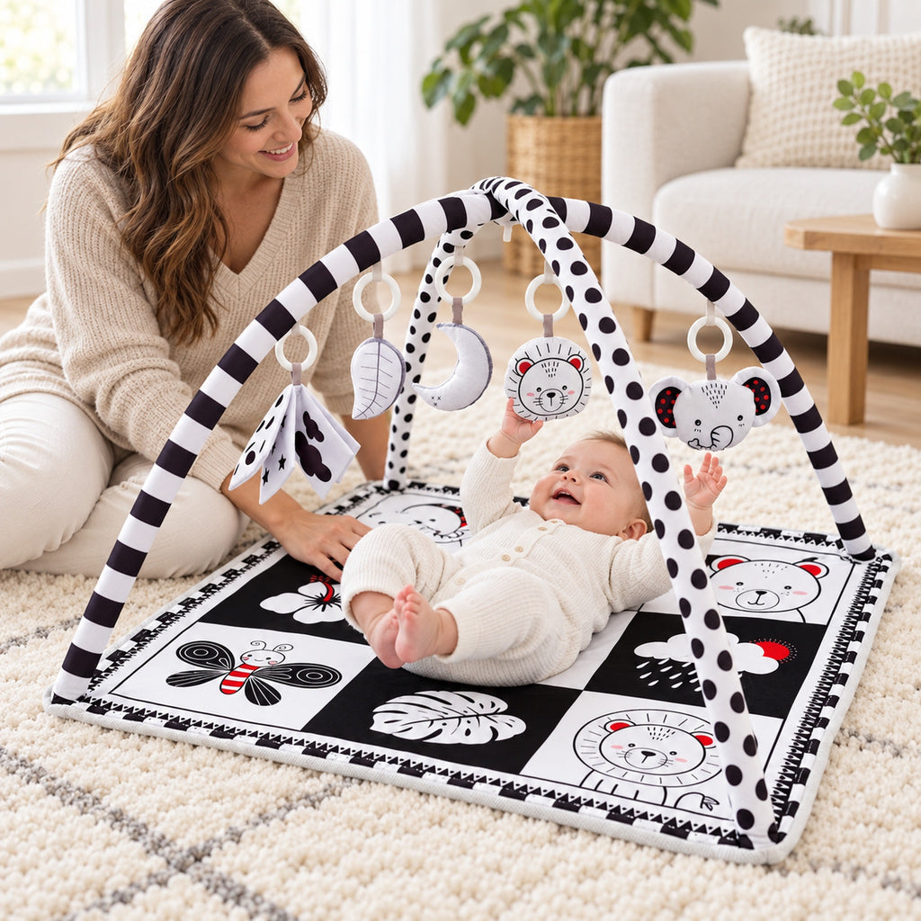 Awake baby playing under the black and white Lumiwee Domino gym beside a parent