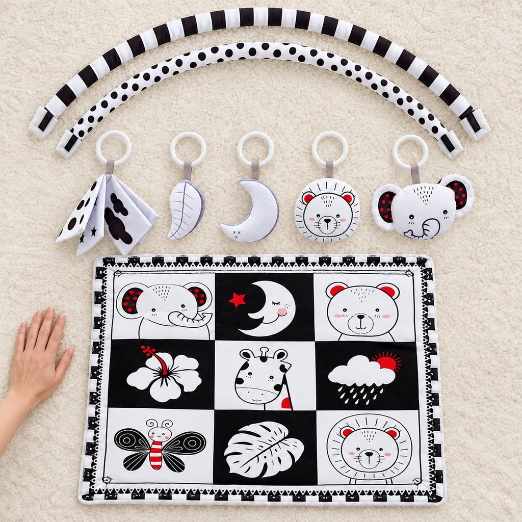 Lumiwee Domino mat, two arches, four rattles and cloth book beside an adult hand