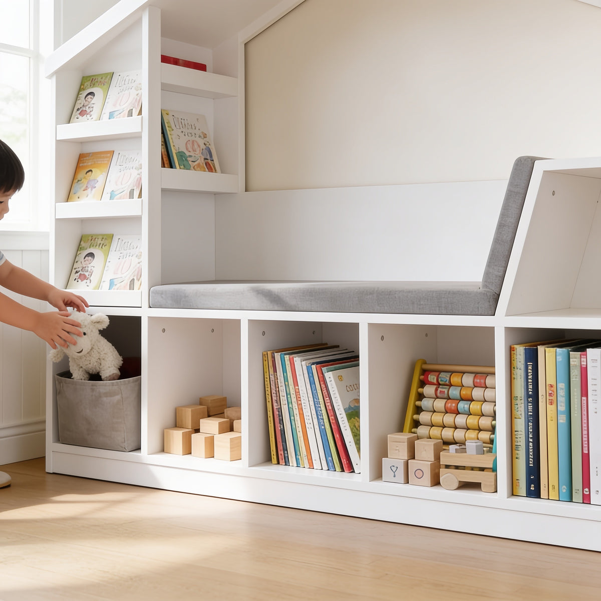 Lumiwee Hazel white kids bookcase with reading nook: child dropping a plush toy into a cubby bin