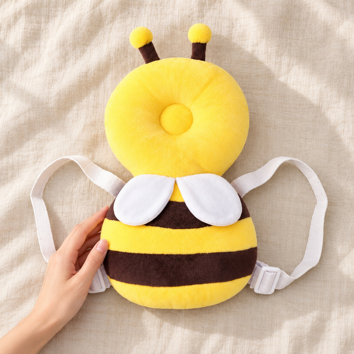 Bee cushion backpack beside an adult hand for scale