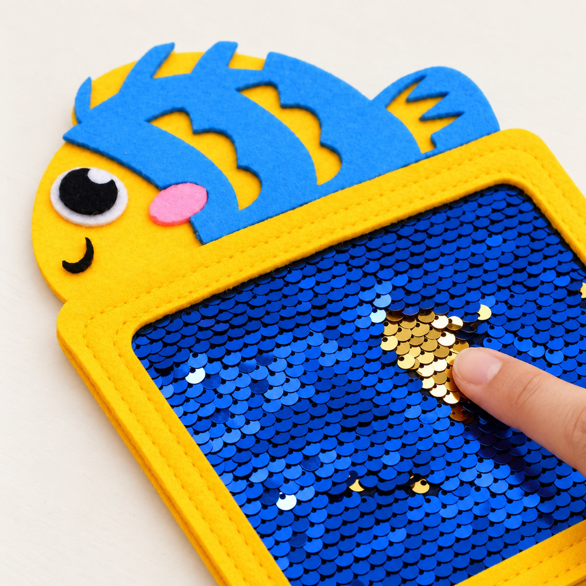 Adult finger flipping sequins on the fish texture mat