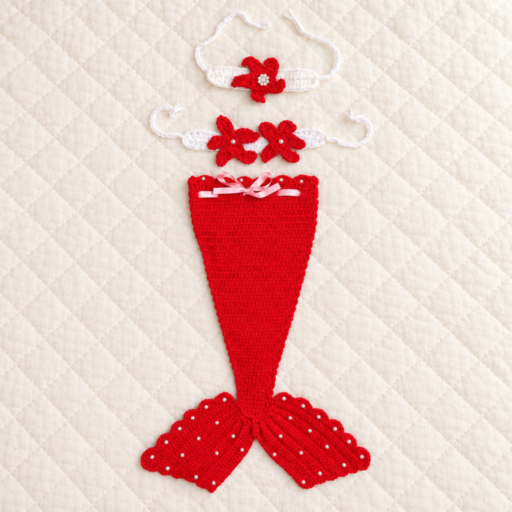Lumiwee red crochet mermaid tail with matching starfish headband and chest accessory on an ivory quilt