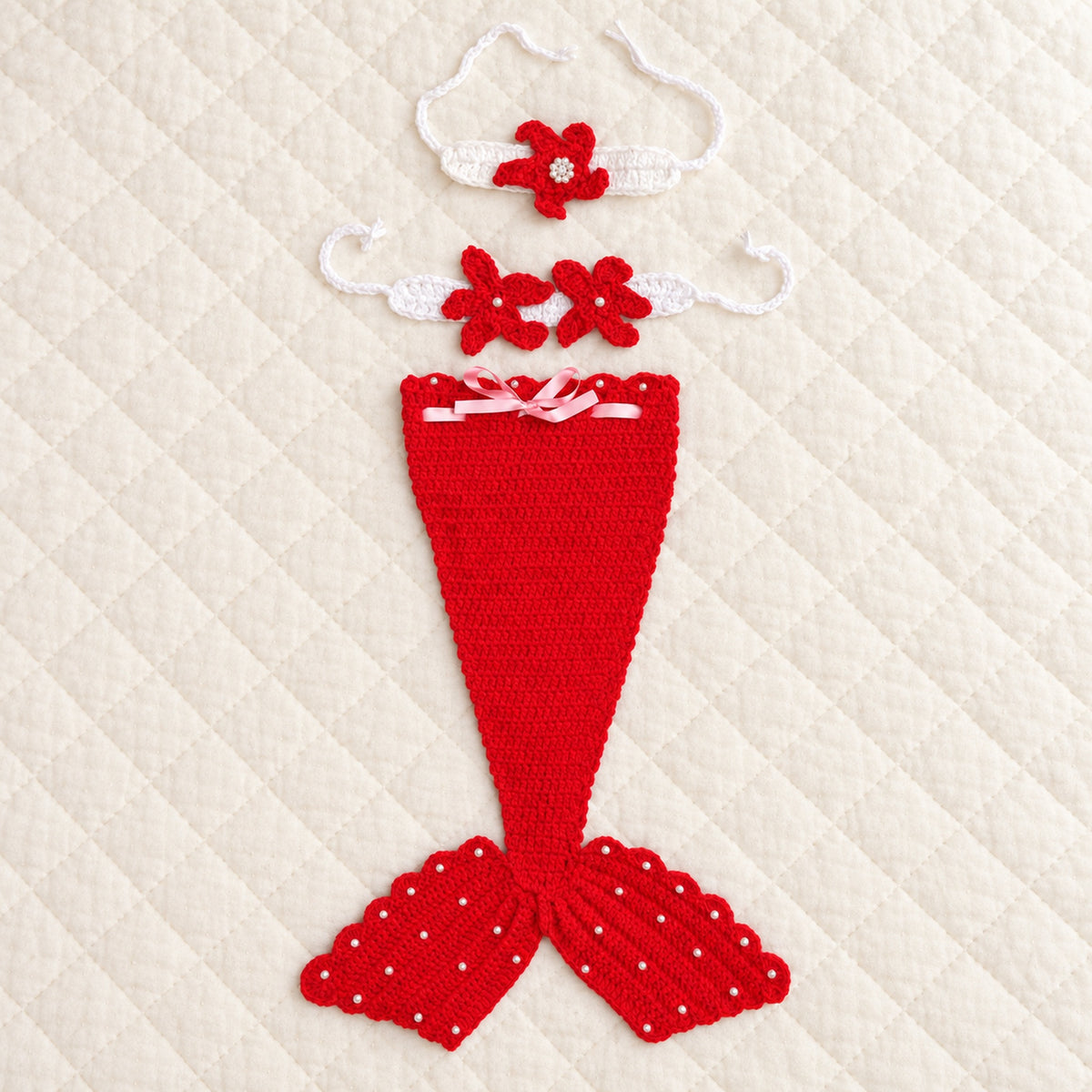 Lumiwee red crochet mermaid tail with matching starfish headband and chest accessory on an ivory quilt