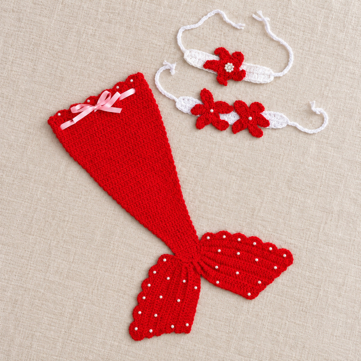 Red crochet mermaid photo-prop set arranged on oatmeal linen