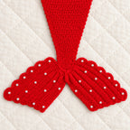 Close-up of red crocheted scalloped fin and pearl embellishments