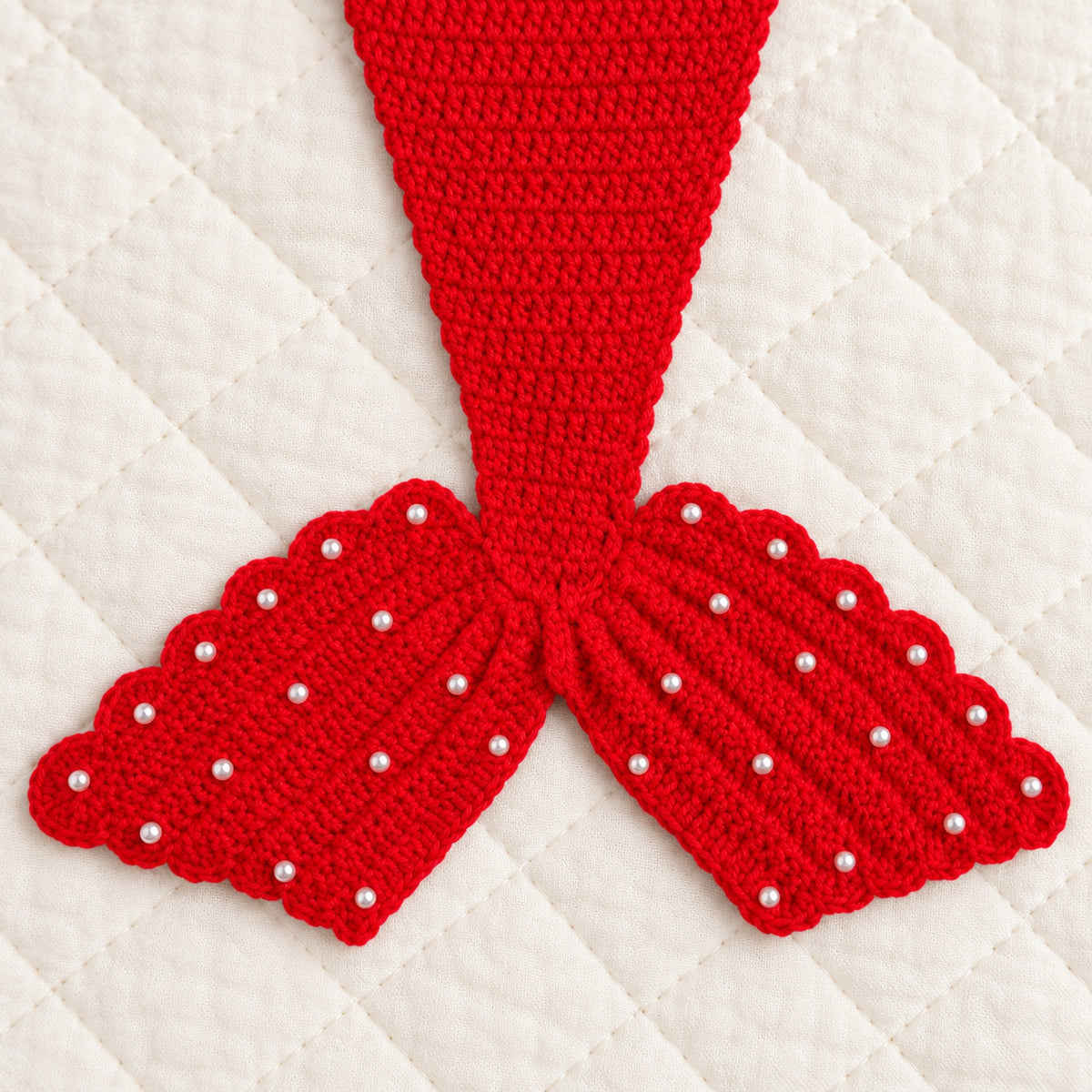 Close-up of red crocheted scalloped fin and pearl embellishments