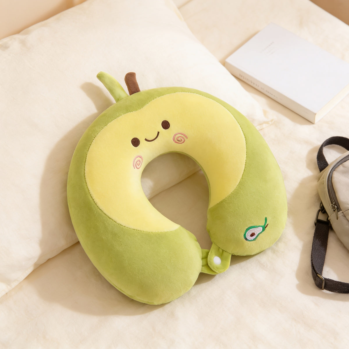 Lumiwee Nap U-shaped memory foam travel pillow: avocado pillow next to a paperback for scale
