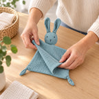 Adult folding the blue bunny muslin lovey for a bag