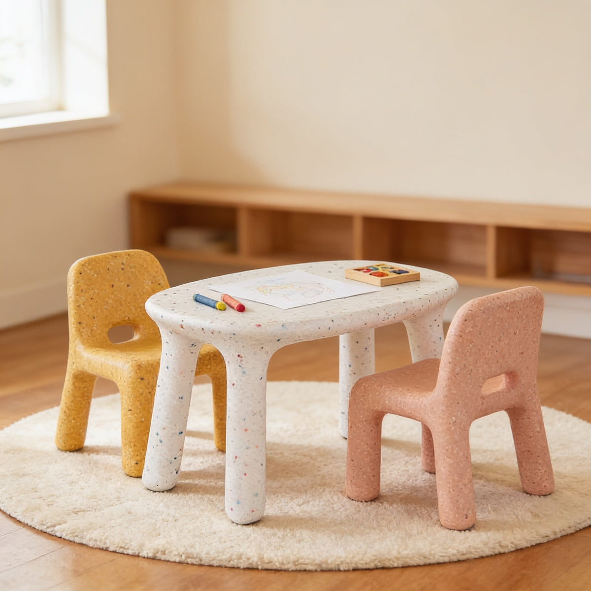 Lumiwee Pebble kids table and chair set: white speckled table with a yellow and a pink chair in a sunlit playroom