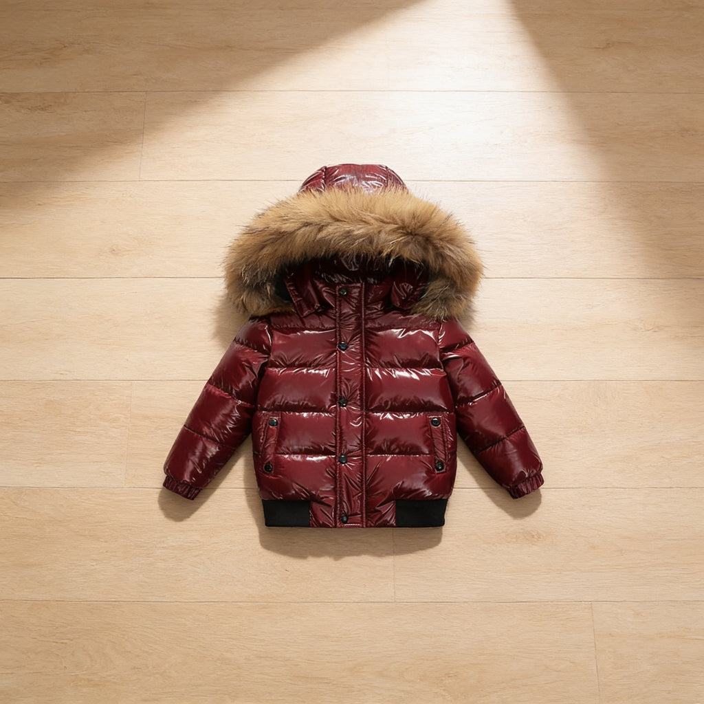 Lumiwee Puffin kids hooded puffer jacket: the wine red puffer jacket laid flat on a wood floor