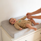 Lumiwee Rex dinosaur baby bodysuit: straightening the sleeve cuff on a changing pad