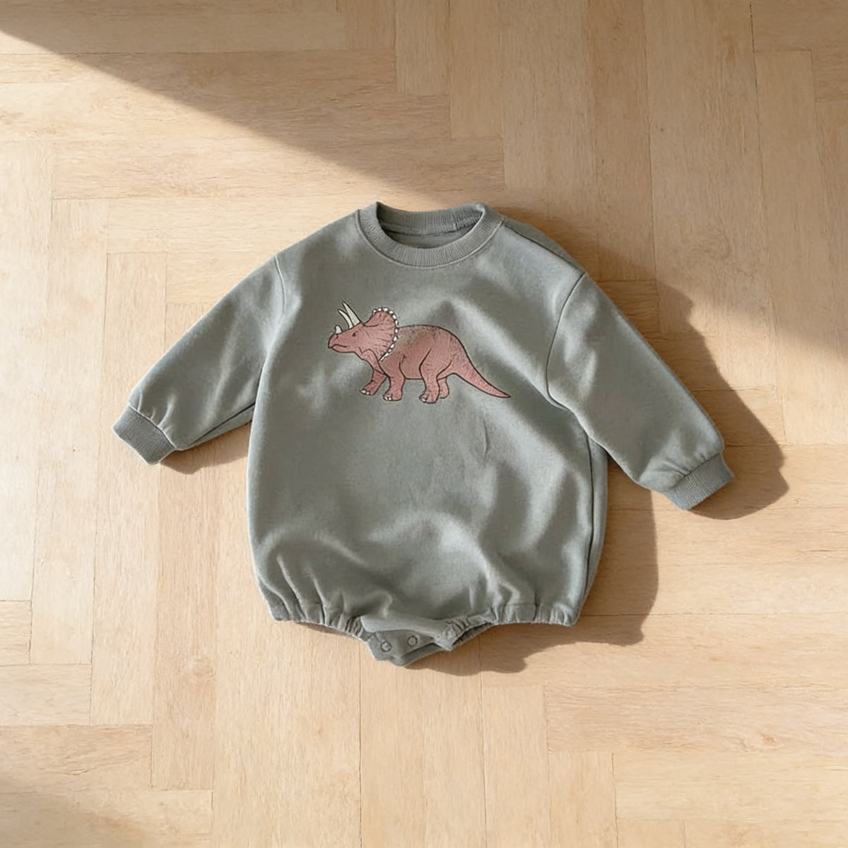 Lumiwee Rex dinosaur baby bodysuit, Triceratops option, in a bright room