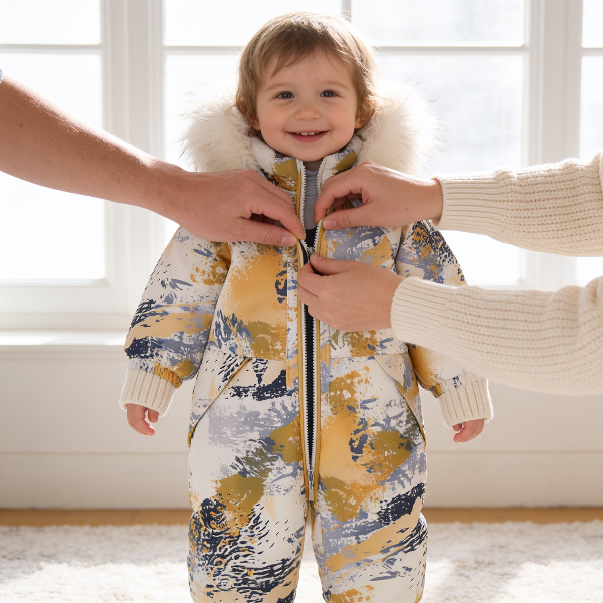 Lumiwee Snowdrop toddler hooded snowsuit: parent zipping up the snowsuit on a toddler