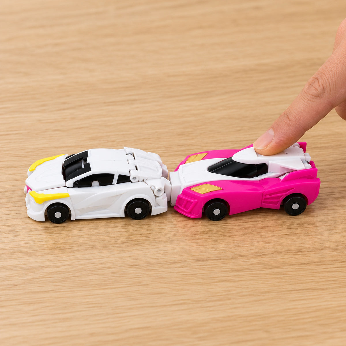 Adult finger pushing the pink car into the rear of the white car