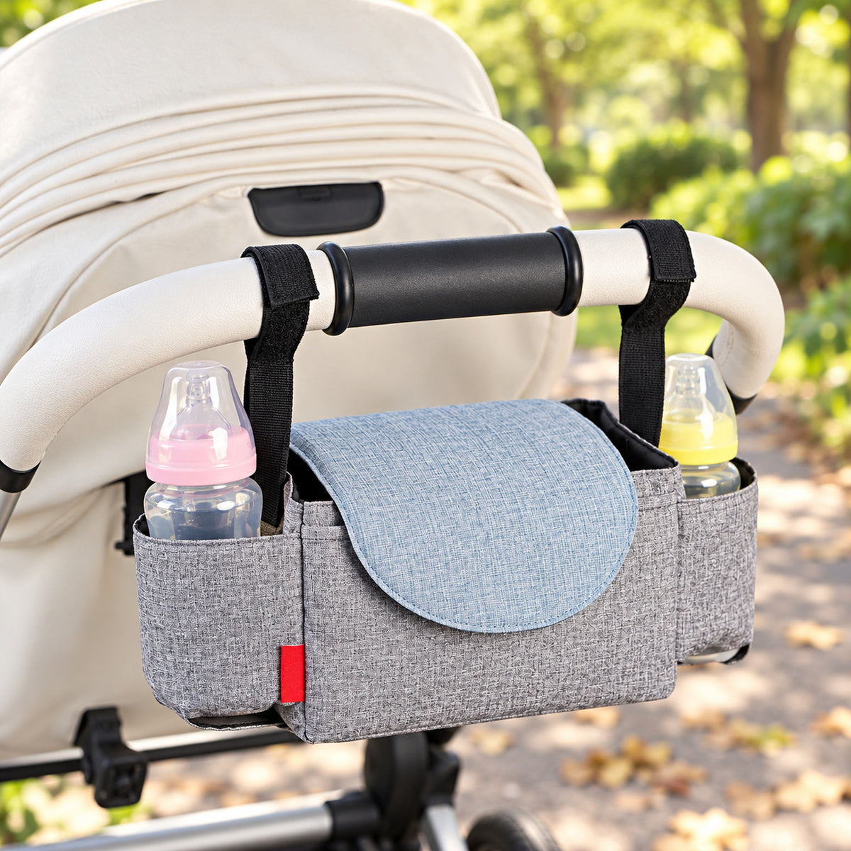 Sparrow gray stroller caddy attached to a cream stroller with two capped bottles
