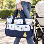 Adult carrying the Deep Blue Starling tote by its handles beside a stroller