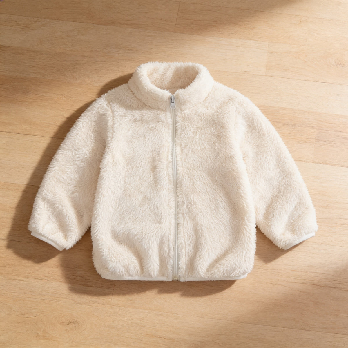 Lumiwee Teddy kids plush jacket: the cream plush jacket laid flat on a wood floor