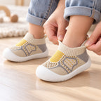 Parent gently stretching the Khaki sock shoe collar around a toddler's ankle