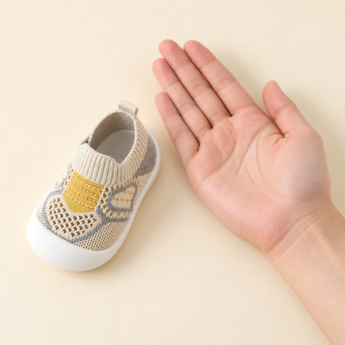 One Khaki sock shoe beside an adult palm for scale