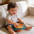 Lumiwee Twirl 360 rotating baby bowl: toddler snacking from the bowl on the sofa