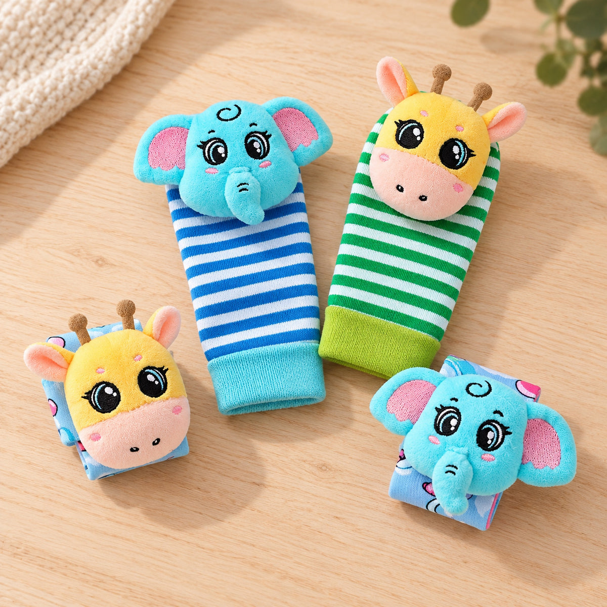 Giraffe and Elephant four-piece rattle set on a pale wooden table