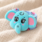 Elephant wrist rattle close-up showing embroidered face and patterned fabric band