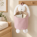 Pink and White Bunny diaper caddy holding wipes and cream on a wall hook beside a changing dresser