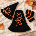 Black and orange crochet witch hat, lace-up cloak and striped socks in an autumn flat-lay