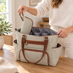 Adult lowering a matching bottle pouch into the open Khaki diaper tote